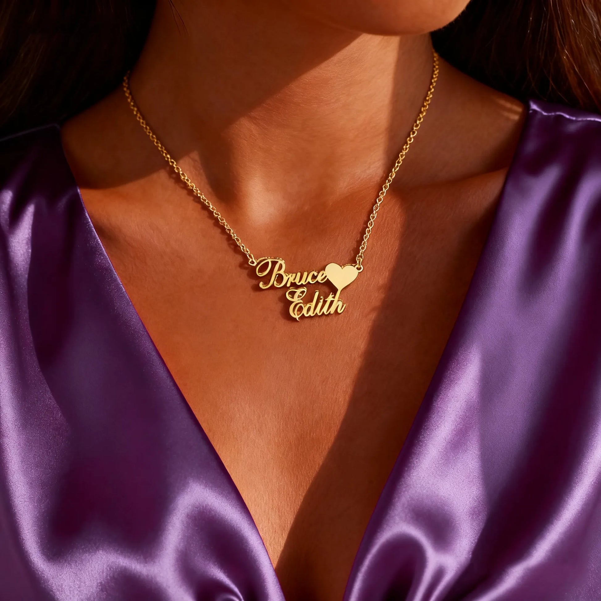 Woman wearing custom double-name heart necklace in gold, cursive nameplate
