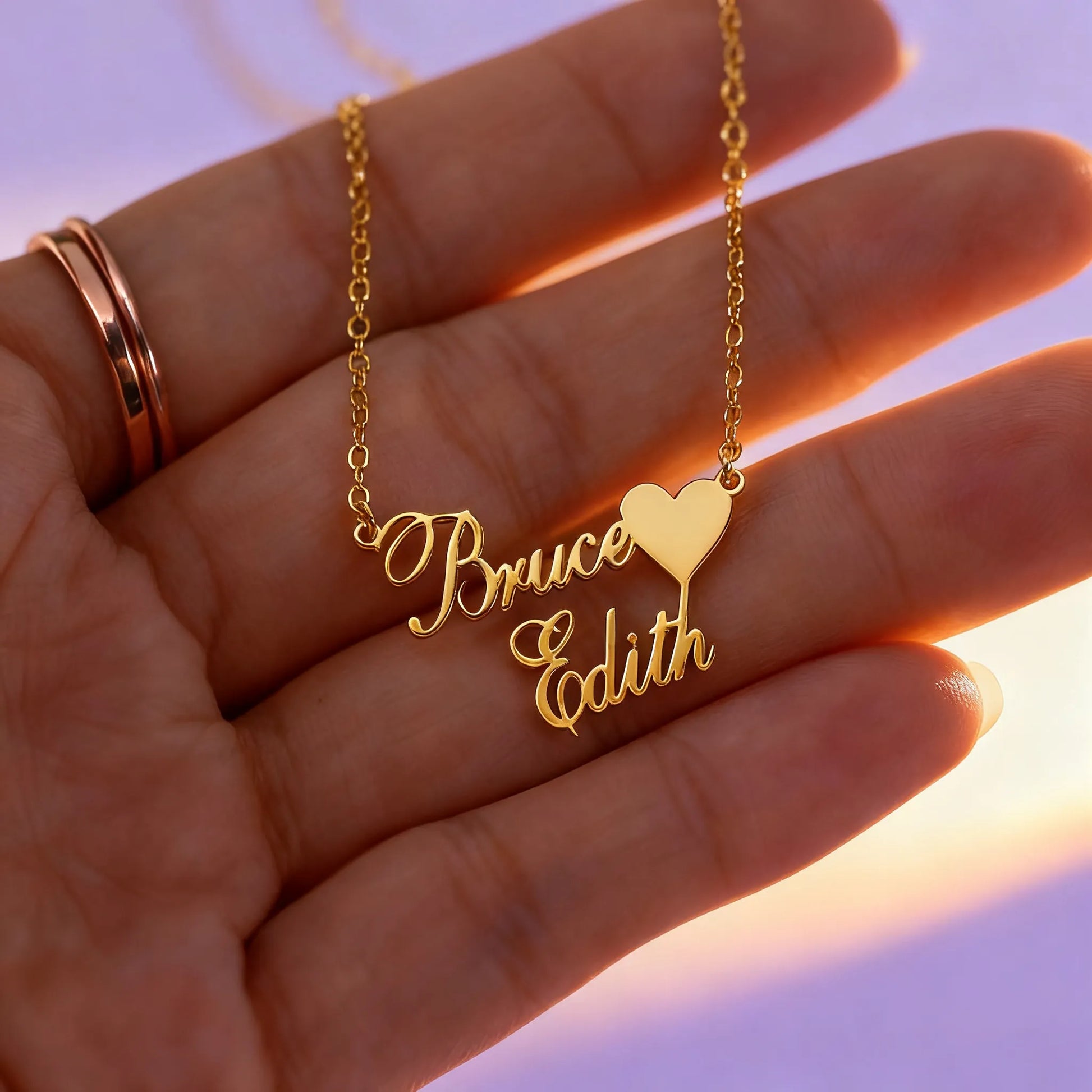 Hand holding personalized two-name heart pendant necklace, gold chain